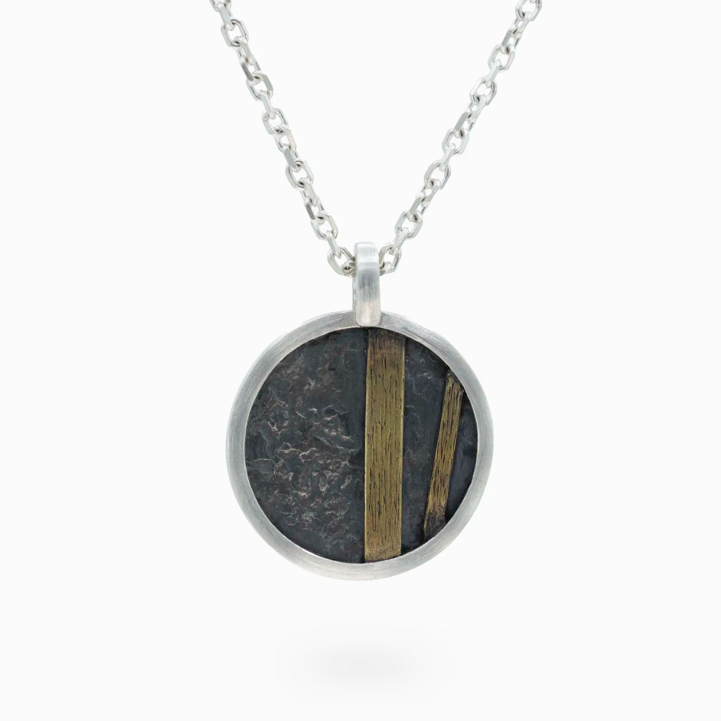 Sterling Silver round silver pendant with textured oxidized details and brass accents.