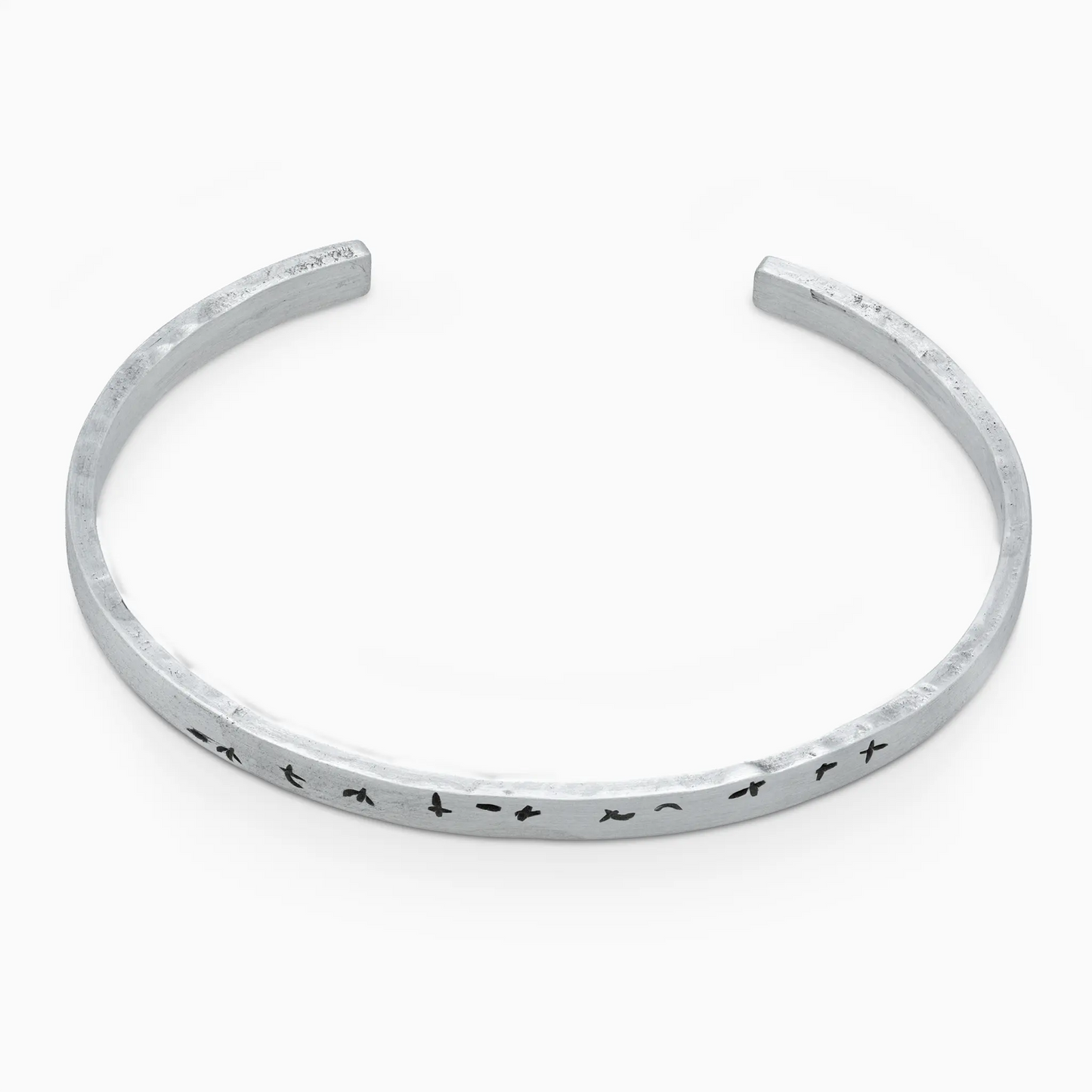 Minimalist silver bracelet with bird patterns, handcrafted open cuff, lightweight design.