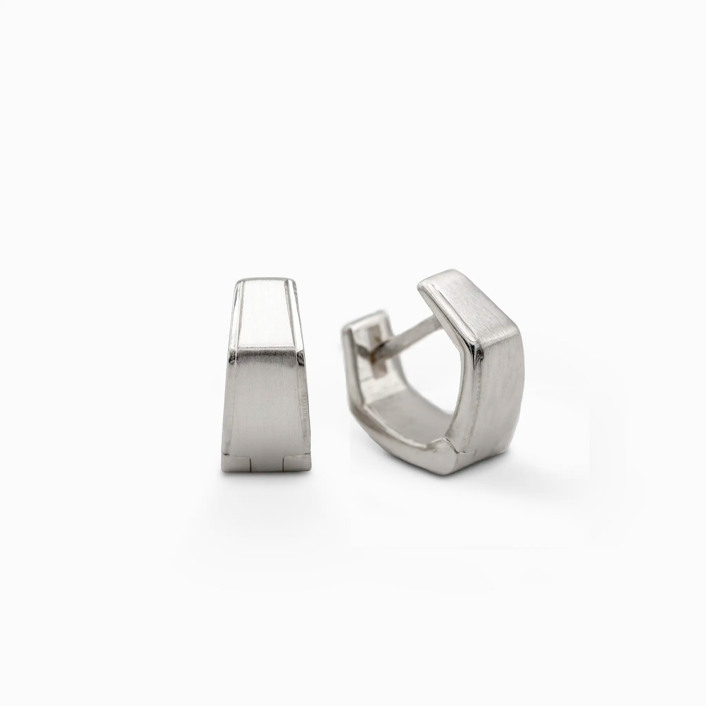 Close-up of Ekko earrings, silver huggie hoops with angular design, one upright and one slightly open to show clasp.