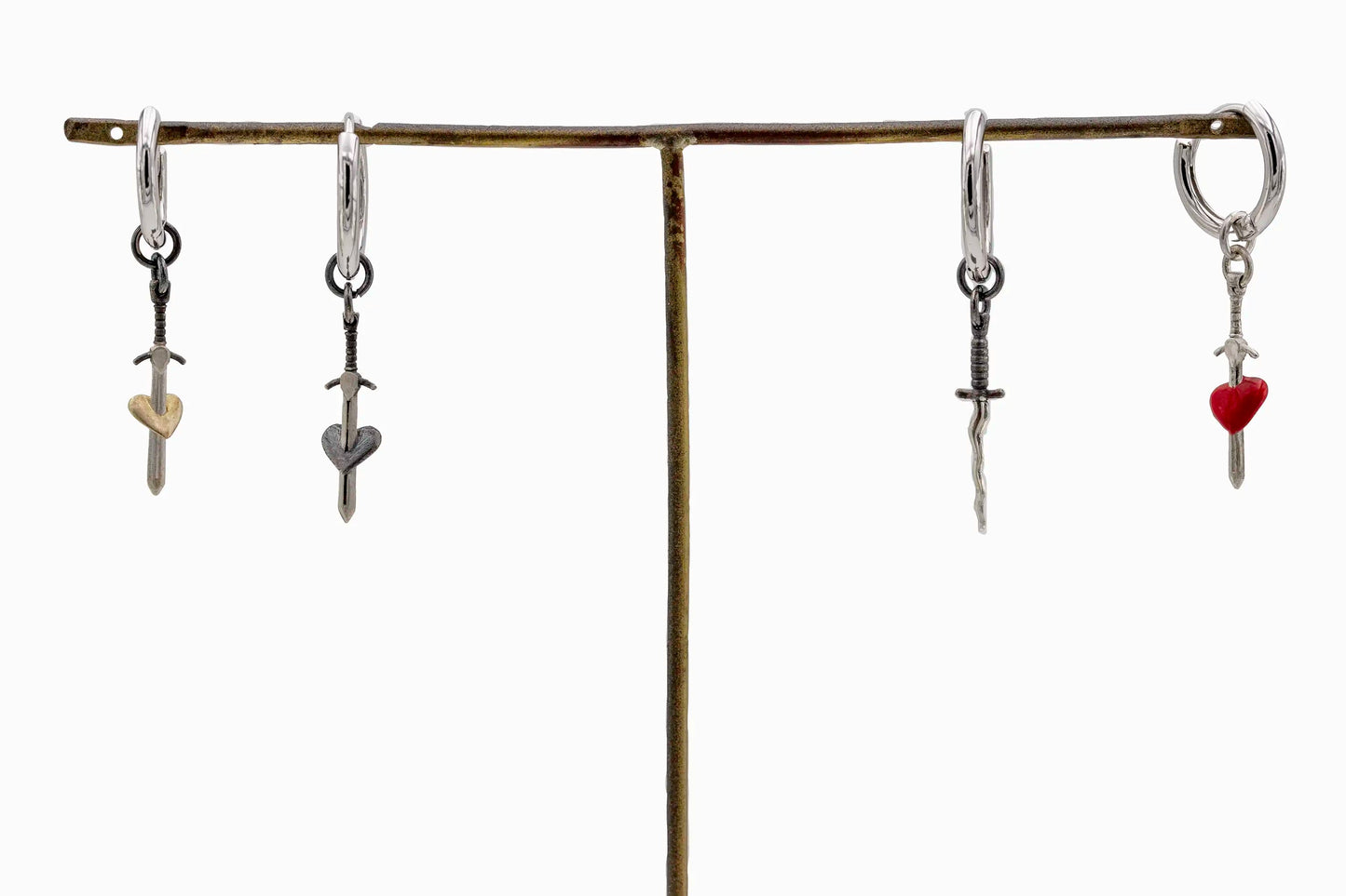 Set of sterling silver hoop earrings with sword pendants: gold heart, black heart, wavy blade, and red heart, handcrafted