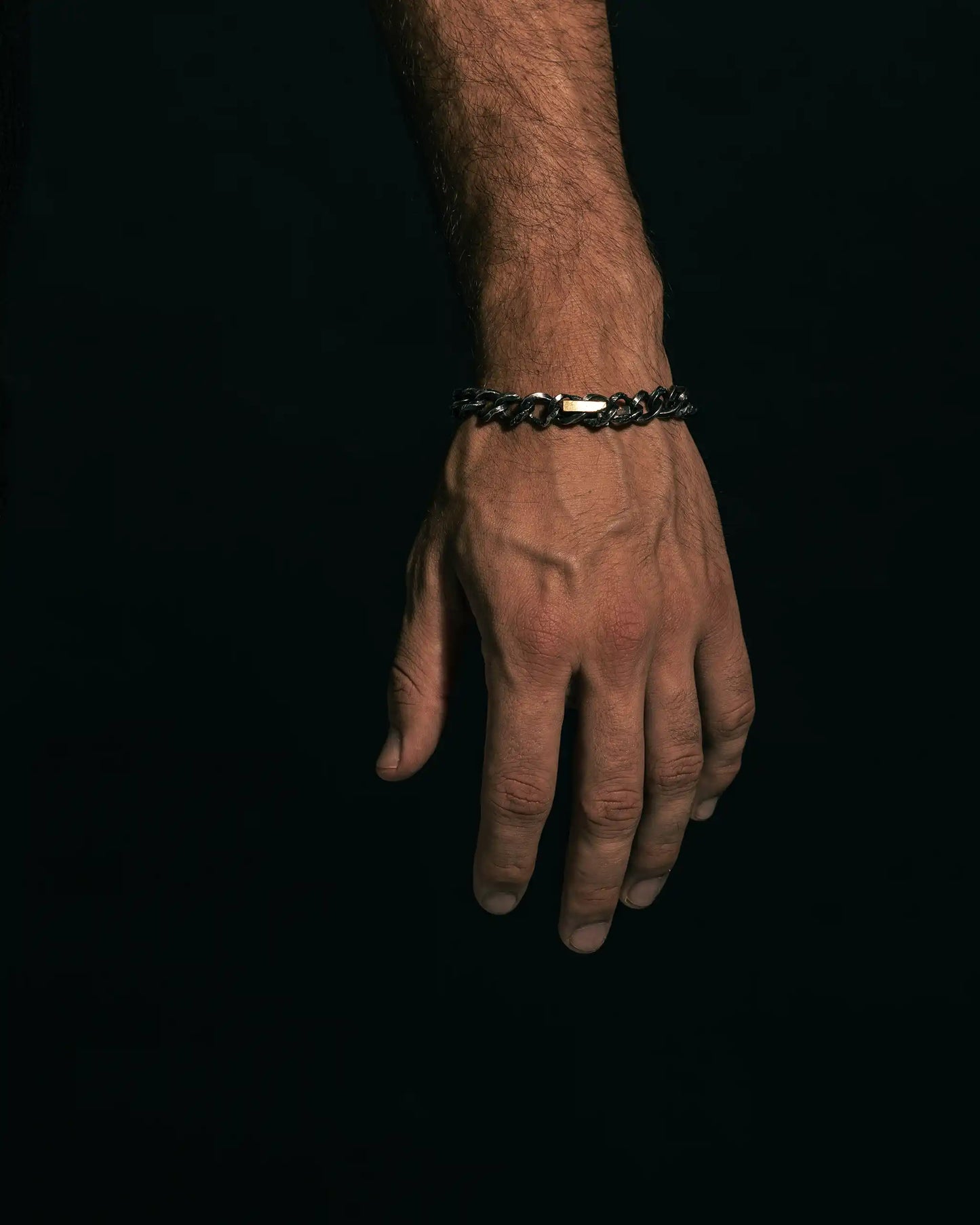 Oxidized silver bracelet with intricate links and a polished gold-covered cross centerpiece for bold contrast.