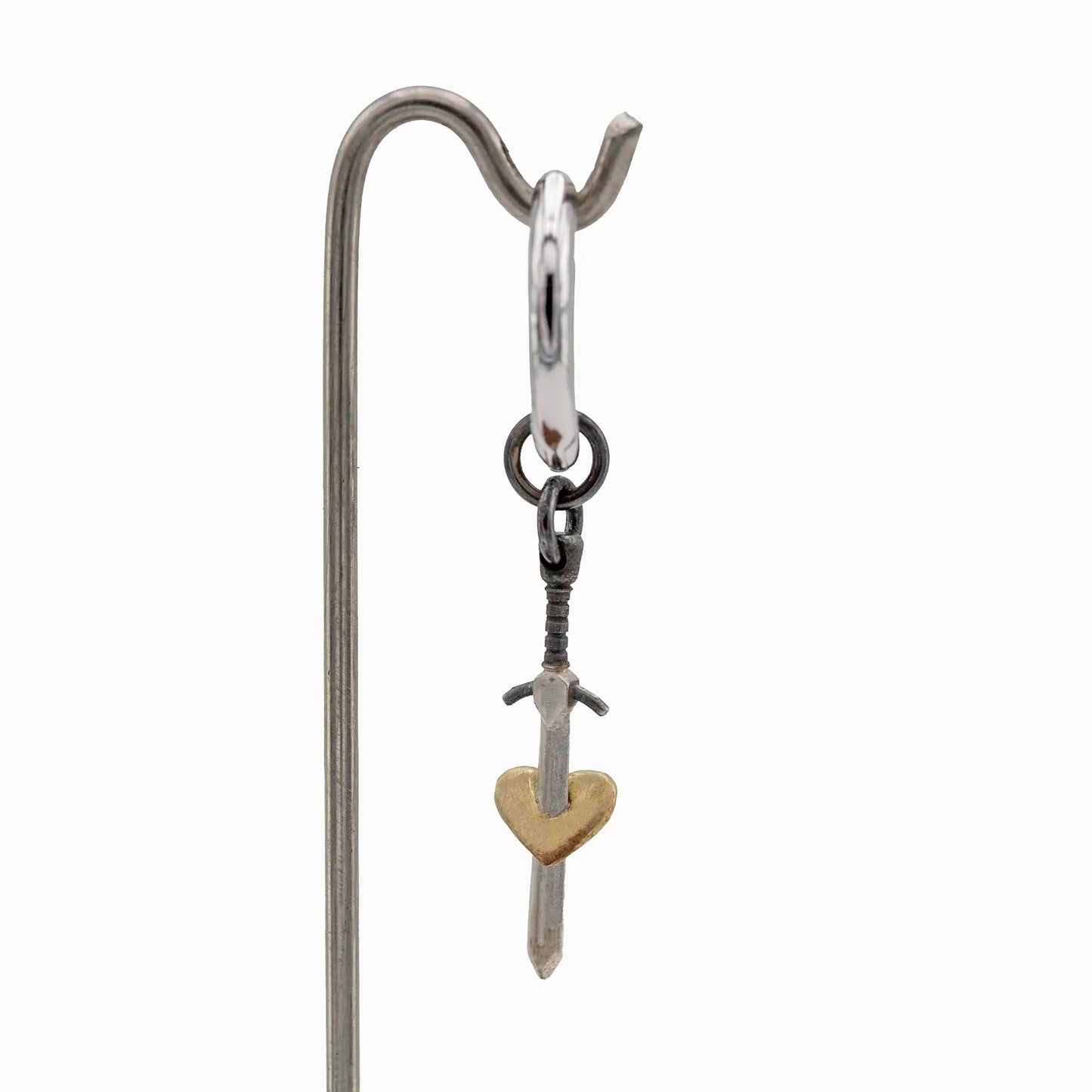 Silver hoop earring with a gold-plated heart sword pendant.