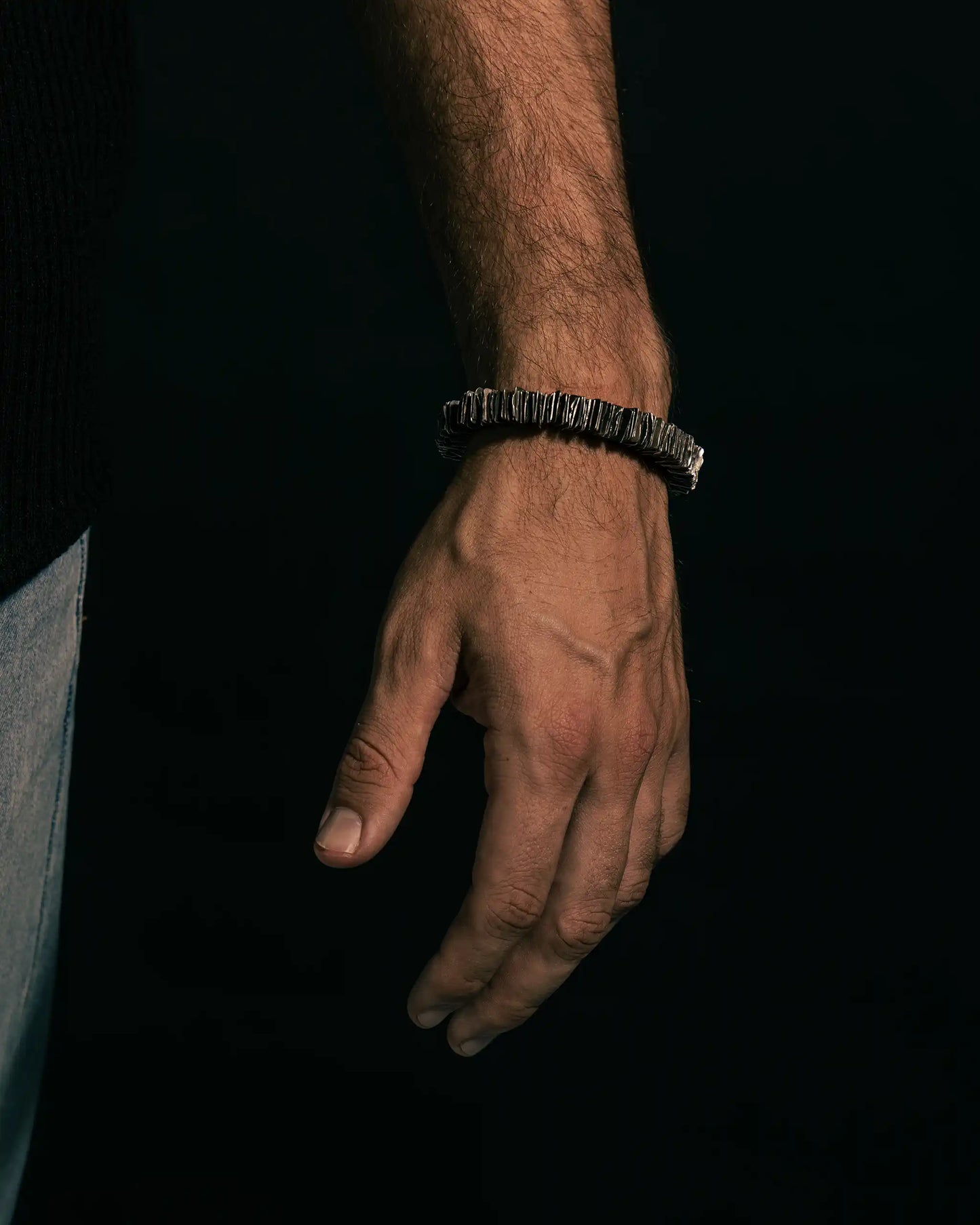 Bold textured silver bracelet worn in a relaxed pose, showcasing artisanal design.