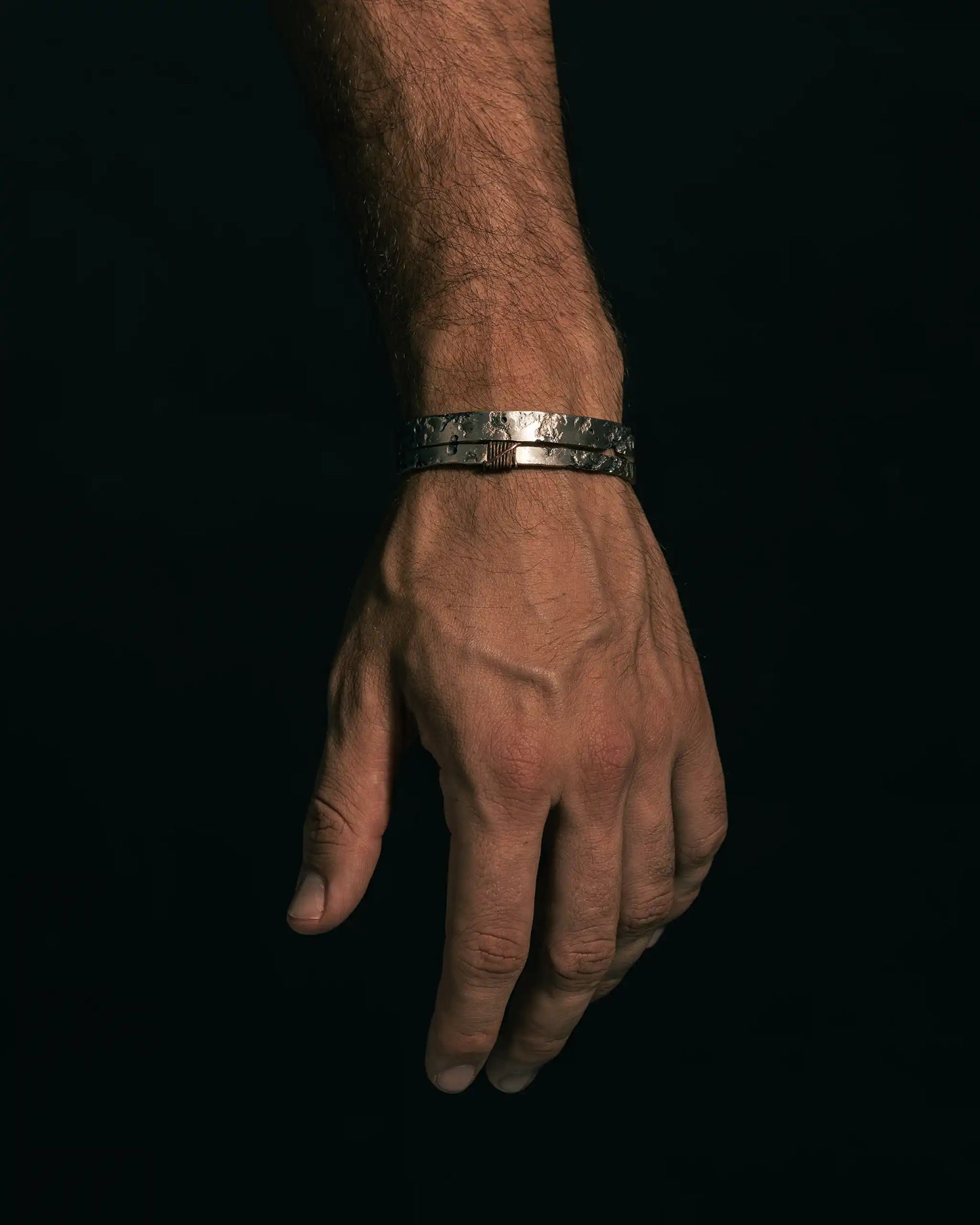 Hand wearing the ISRT bracelet, a textured handmade 925 silver piece, highlighting unique craftsmanship.