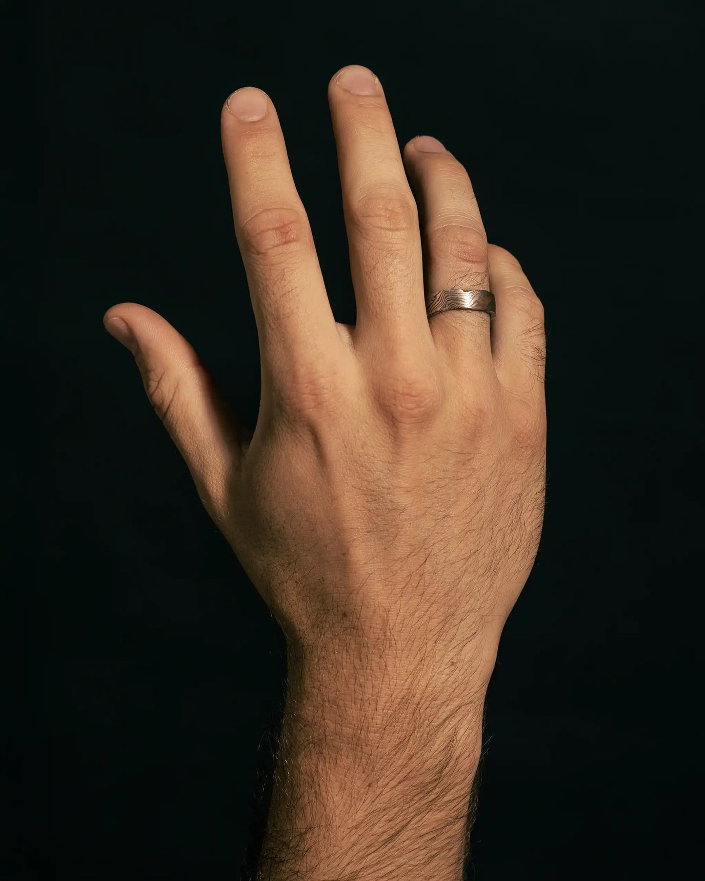 Sterling silver hand wearing the Moku Ring, featuring a natural woodgrain-inspired pattern and refined craftsmanship.