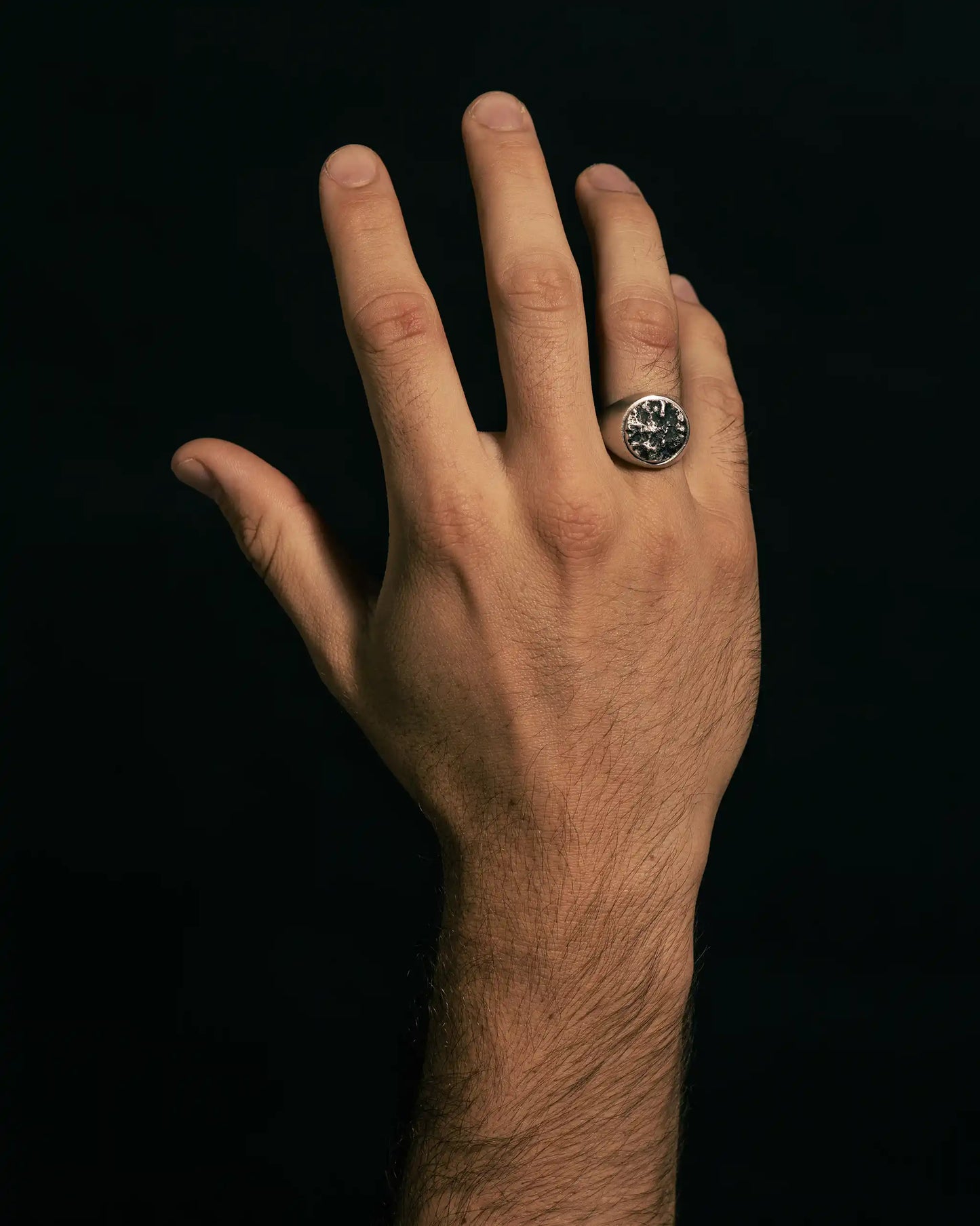 Silver ring on a hand, featuring distinct texture and refined craftsmanship.