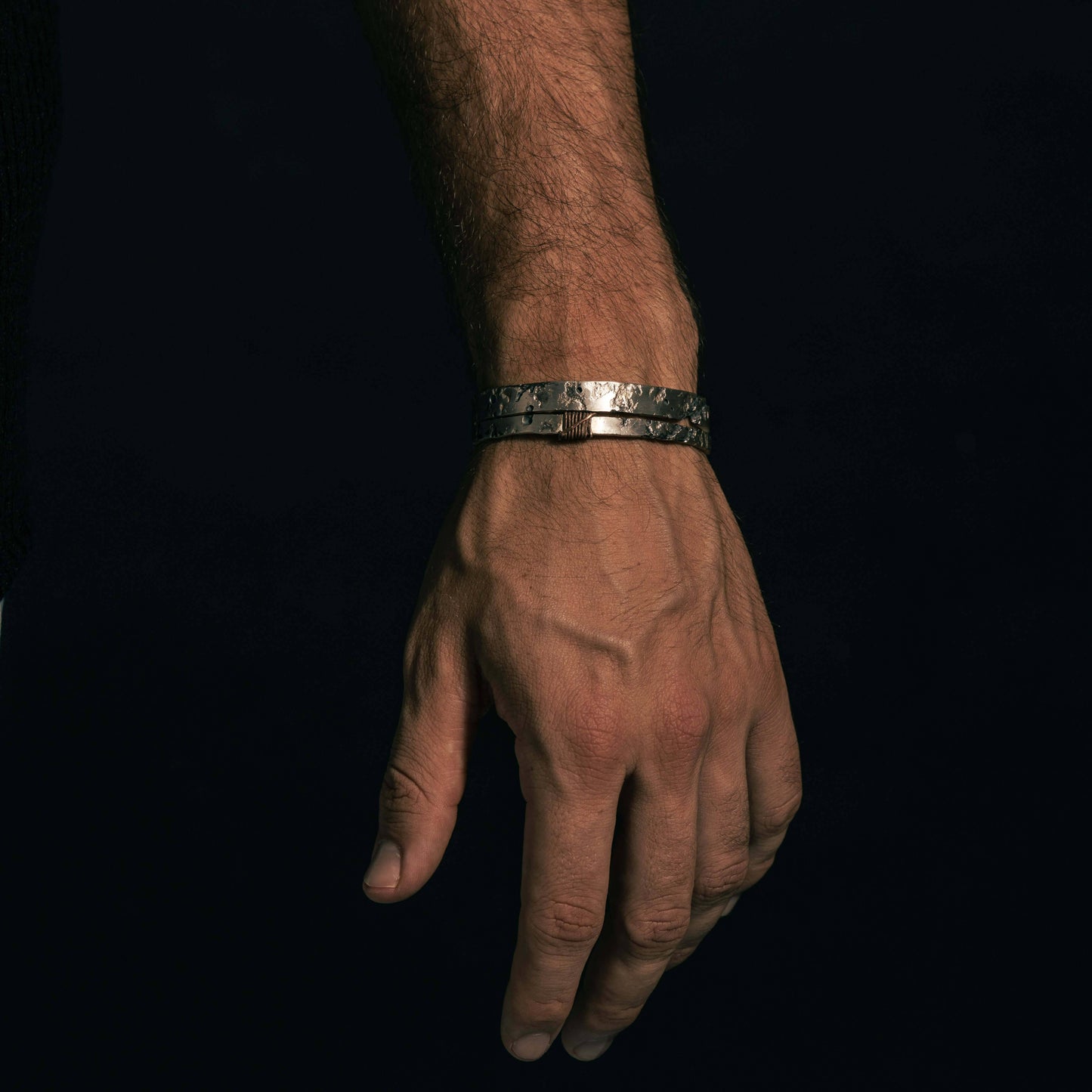 Hand wearing the ISRT bracelet, a handmade 925 silver piece with a textured design, showcasing unique craftsmanship.