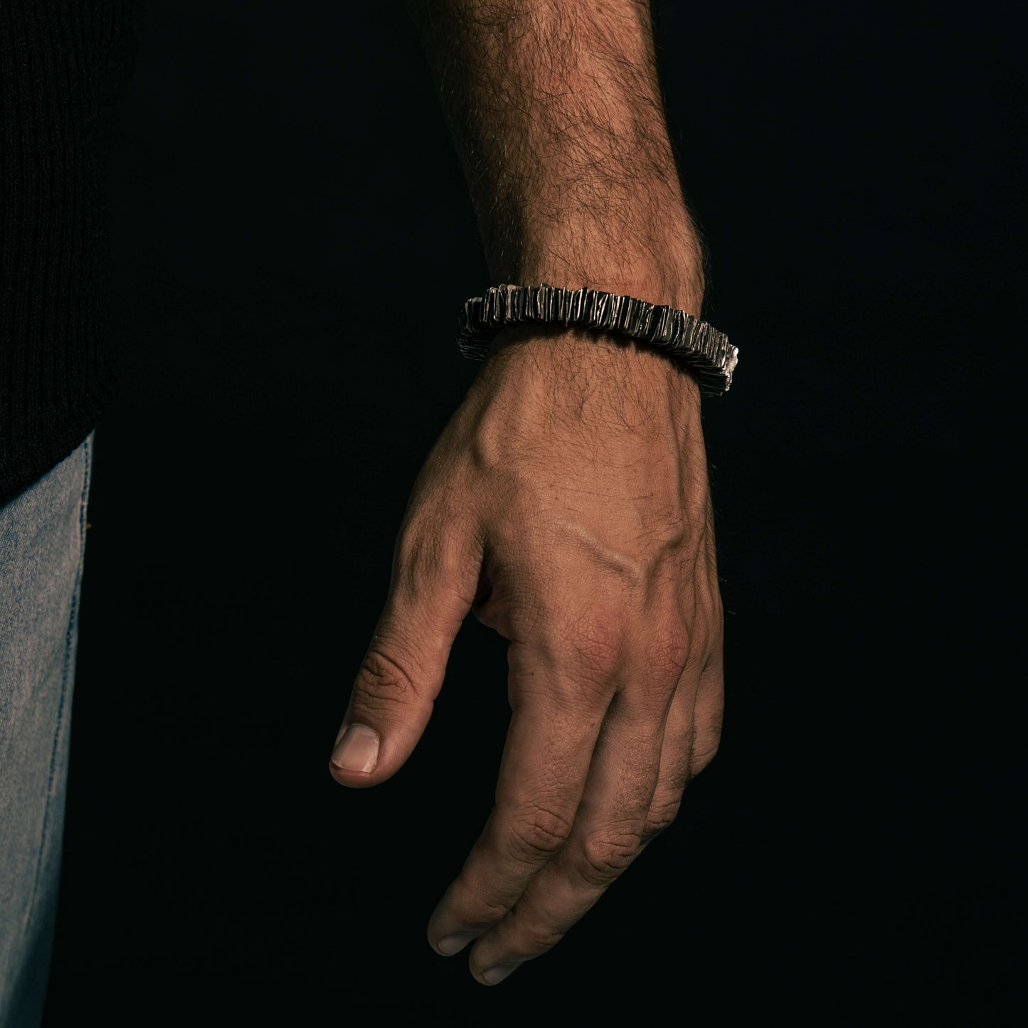 The 'Plates' bracelet worn in a relaxed pose, emphasizing its bold texture and artisanal elegance.