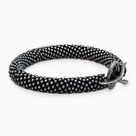 Black textured bracelet featuring a striking silver clasp. A versatile piece combining rugged style with refined elegance.