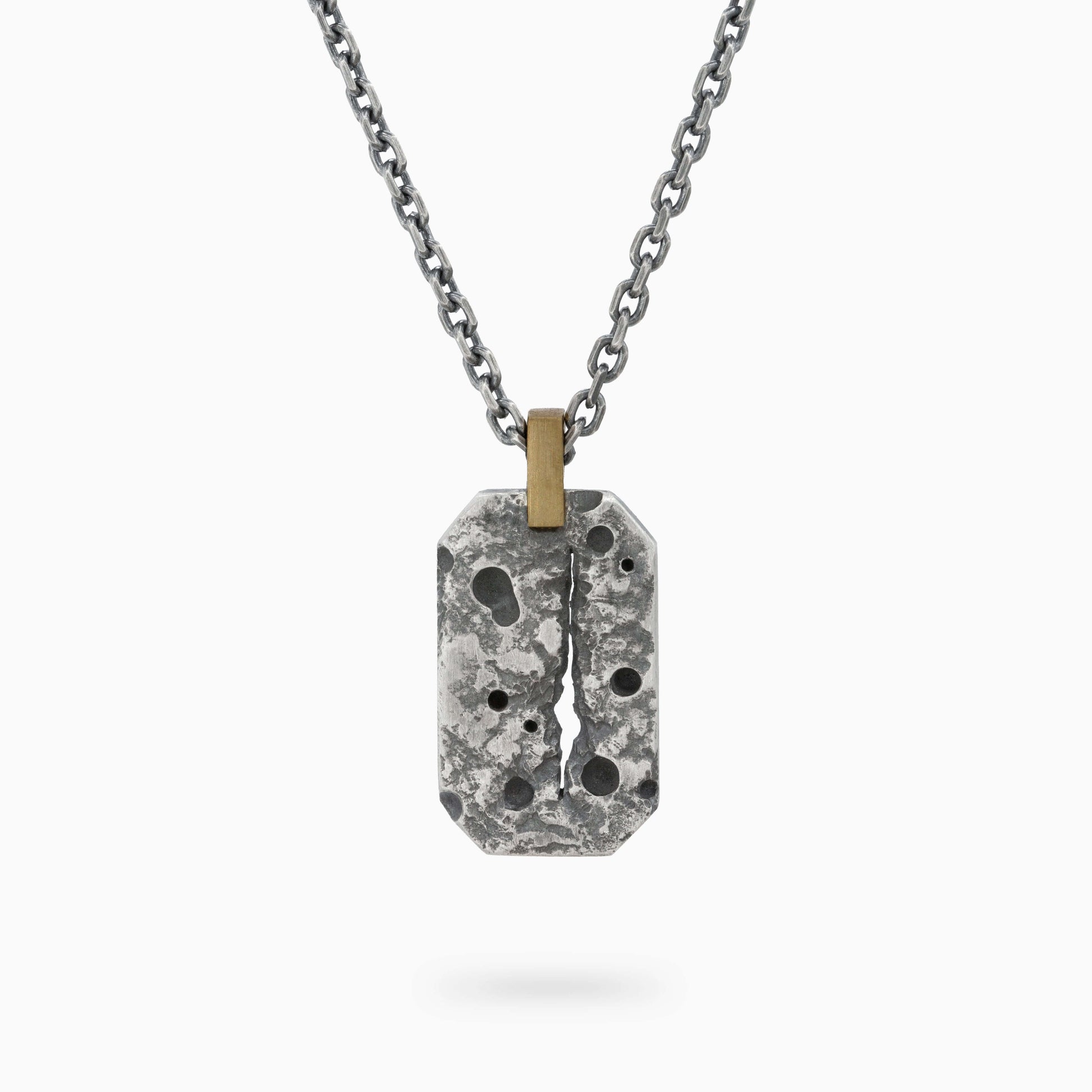 Oxidized sterling silver pendant with a textured, rugged surface and a central crack design, accented with a gold bail on a silver chain.