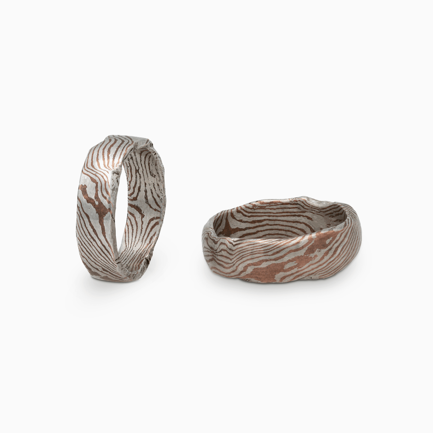 Two Moku Rings side by side, emphasizing their unique, non-replicable designs inspired by natural woodgrain patterns.