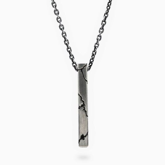 A sleek lightning-inspired pendant with bold cracked details, suspended on a dark, elegant chain. This minimalist piece combines urban edge with refined craftsmanship, making a striking statement.