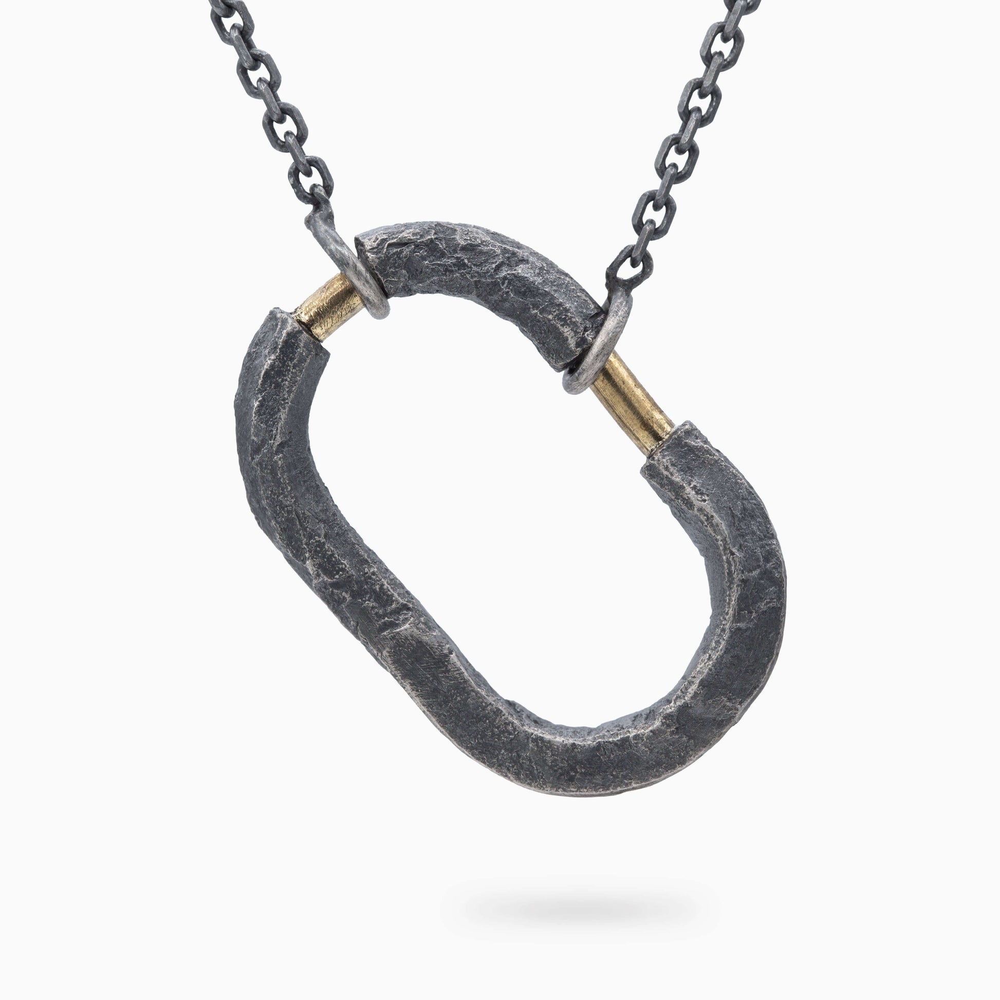 Bold oxidized silver pendant with a rugged, natural texture and gold accents. A striking design that symbolizes strength and connection.