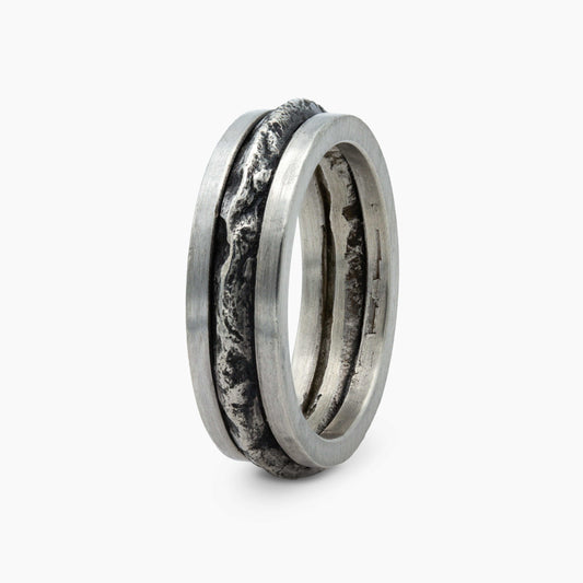 Close-up of a silver ring with a bold, textured band, capturing the essence of rugged mountain terrain. Perfect for a refined yet adventurous look.